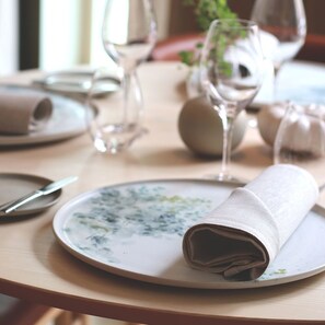 Una mesa puesta con un plato, una servilleta doblada y una cuchara.