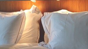 Una cama con sábanas blancas y cabecera de madera.