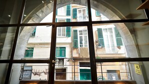 A view through a window with a metal frame, looking out onto a building with multiple windows and balconies. - Lussuoso Loft dei Giustiniani Acquario (Genoa)