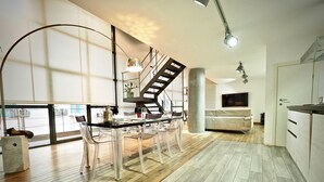 A modern kitchen with a dining area, wooden floors, and a staircase. - Lussuoso Loft dei Giustiniani Acquario (Genoa)