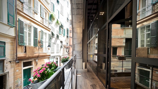 A narrow corridor with a wooden floor, metal railings, and potted plants with pink flowers. - Lussuoso Loft dei Giustiniani Acquario (Genoa)