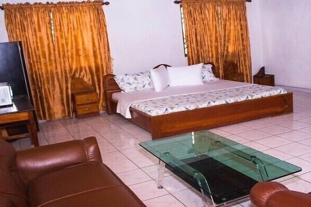 Une chambre à coucher avec un lit, une table basse en verre, un canapé et des rideaux.