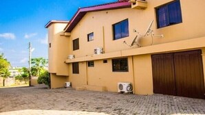 A two-story building with a flat roof, multiple windows, and a paved driveway. - Vinny Hotel (Sekondi-Takoradi)