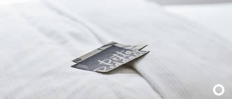 Una cama con un almohadón y un objeto rectangular pequeño encima.