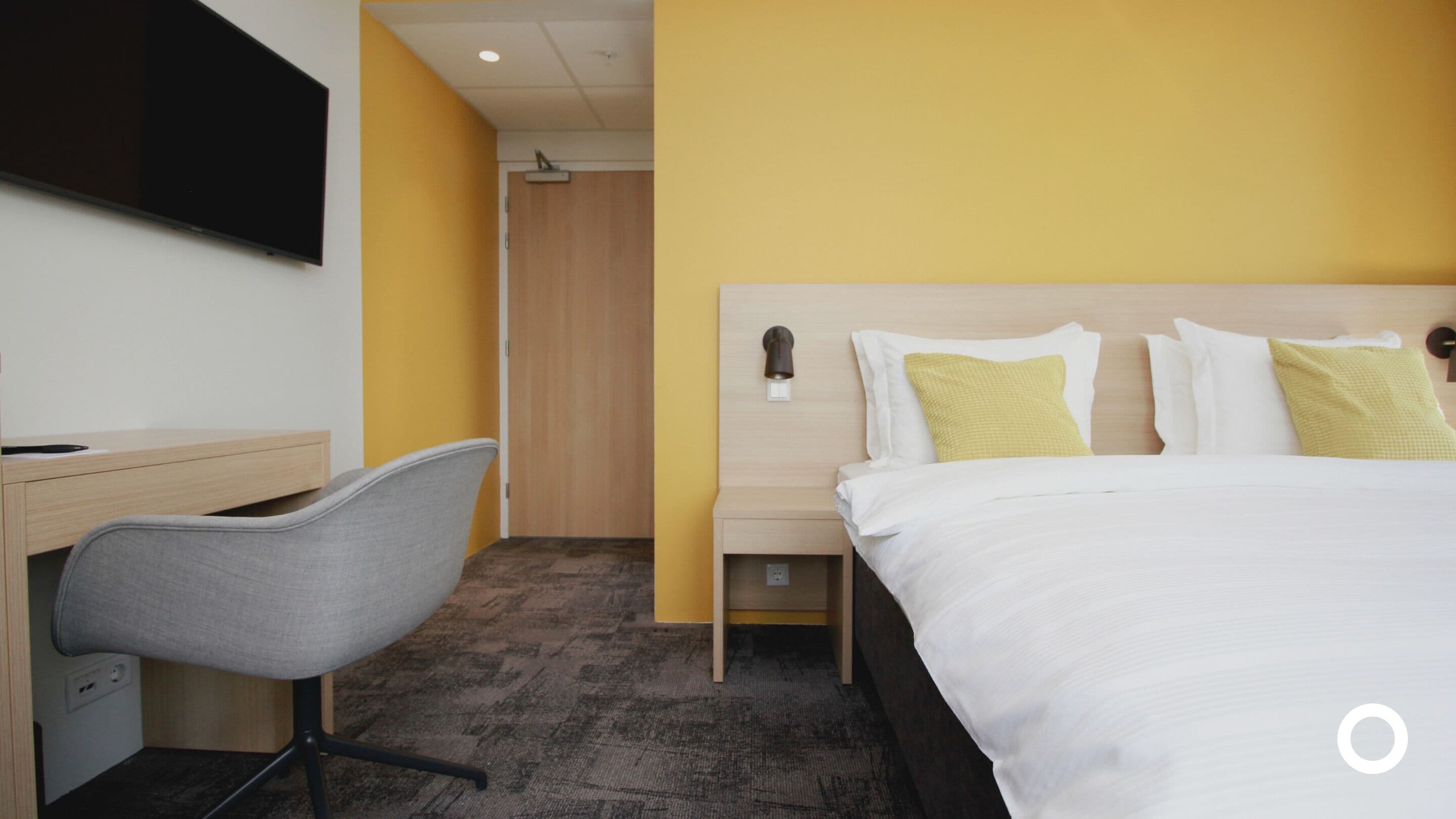 A hotel room with a bed, a desk, and a chair.