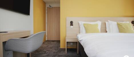 A hotel room with a bed, a desk, and a chair.