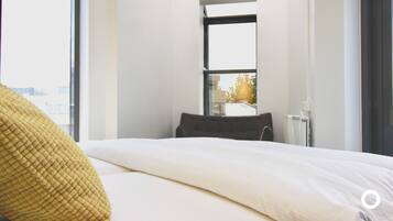 Habitación de hotel moderna con una cama grande, un ventanal con vistas a la ciudad y un radiador.