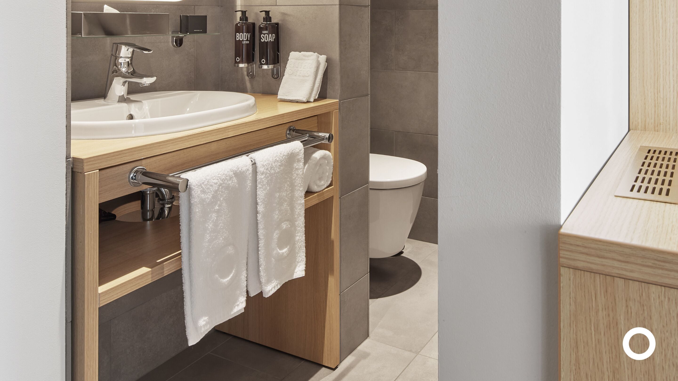 A modern bathroom with a sink, toilet, and towel rack.