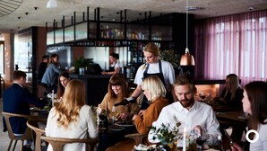 A restaurant with patrons dining, a bartender attending to customers, and a bar area in the background. - Center Hotels Laugavegur (Reykjavik)