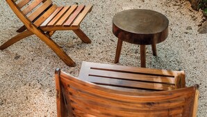 Zona de piscina con dos sillones de madera y una mesita redonda.