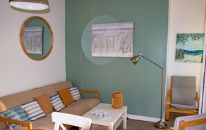 A living room with a green wall, a round mirror, a painting, a floor lamp, a sofa, a coffee table, and a chair.