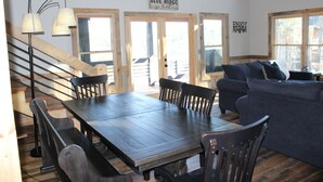 A wooden dining table with chairs, a sofa, and a staircase.