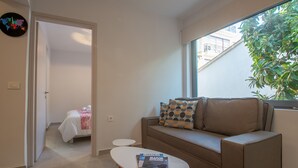 A modern living room with a sofa, a coffee table, and a view of a balcony. - Ithaka Deluxe Home (Zakynthos)