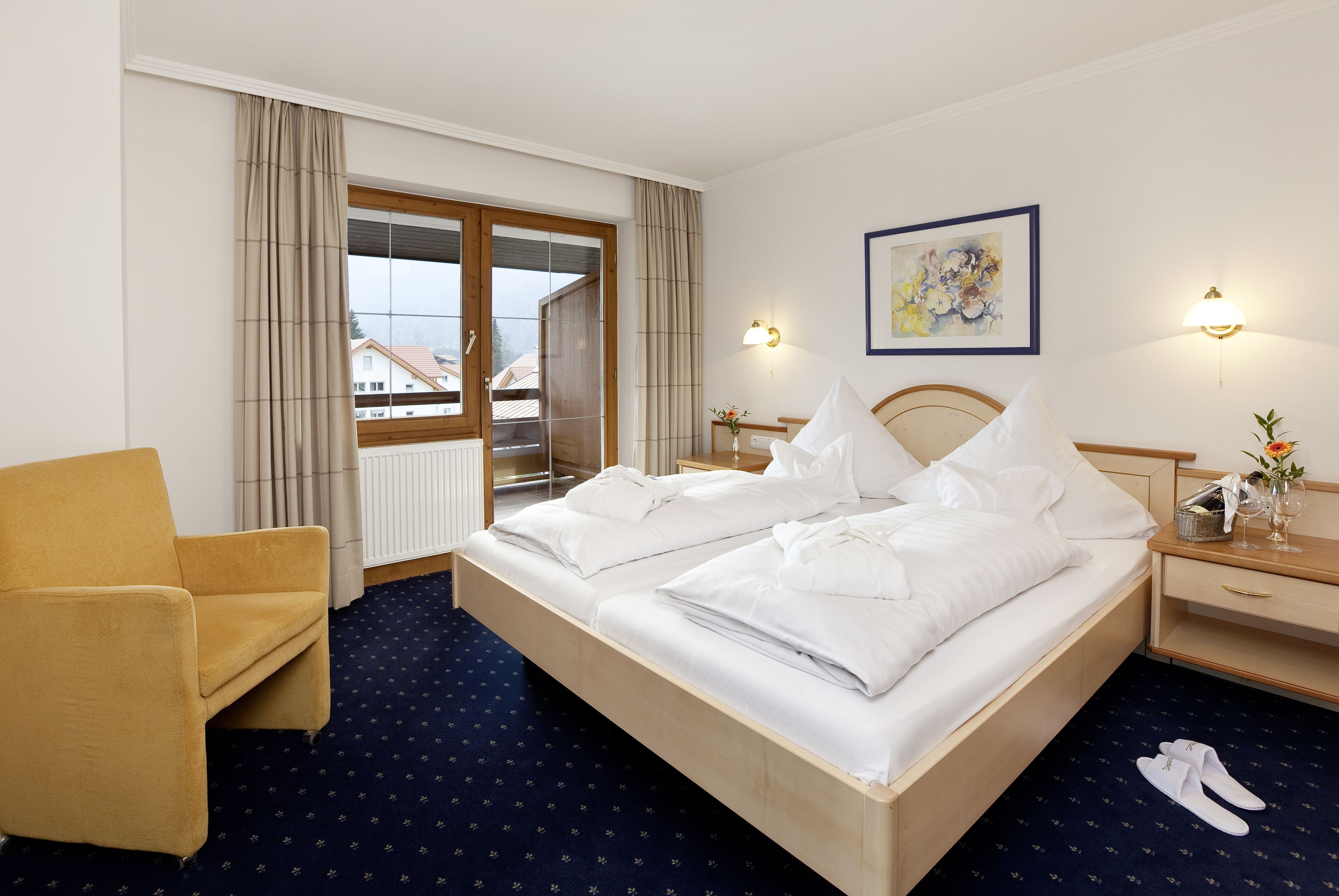 Habitación de hotel con cama, una silla, una mesita de noche y vistas al exterior.