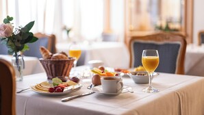 A breakfast setting with a table set for two, including plates of food, a cup of coffee, and a glass of orange juice. - Hotel Filser (Oberstdorf)