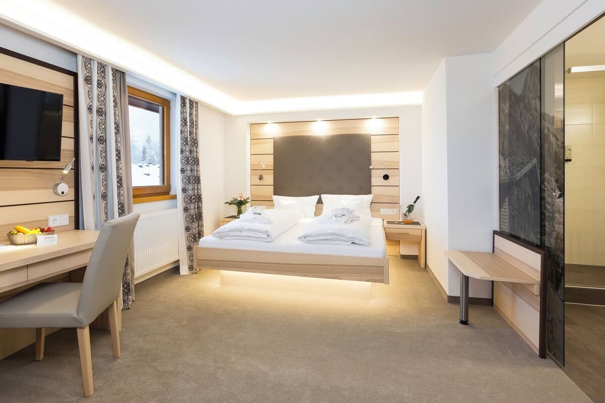 Une chambre d’hôtel moderne équipée d’un lit, d’un bureau, d’une chaise et d’un téléviseur.