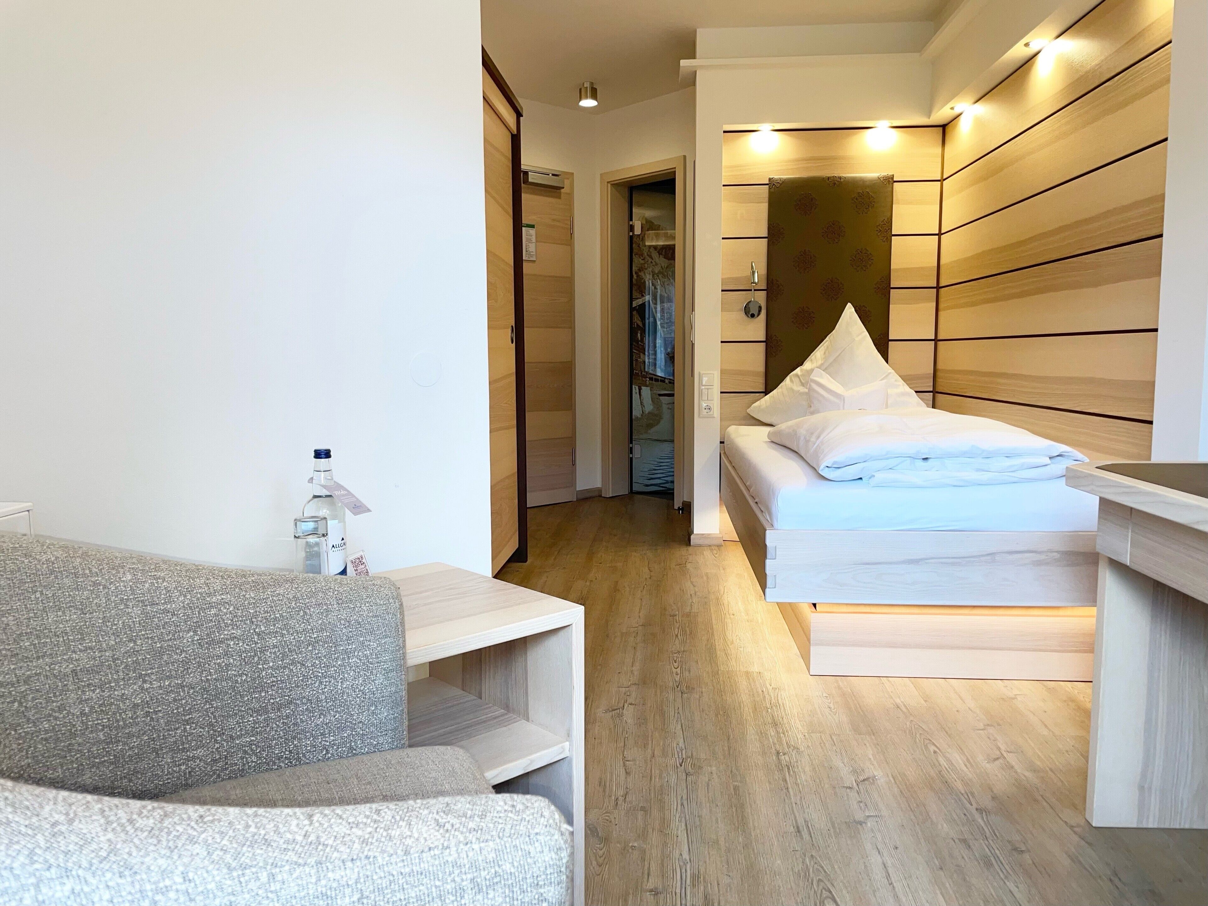 Una habitación de hotel moderna con cama, una mesita y un sofá.