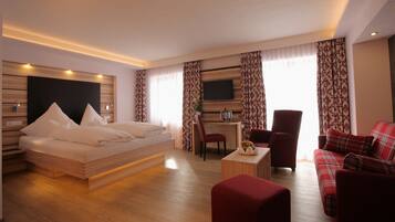 A hotel room with a bed, a desk with a chair, a TV, and a sofa.