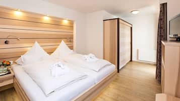A hotel room with a large bed, wooden headboard, bedside tables, and a TV.