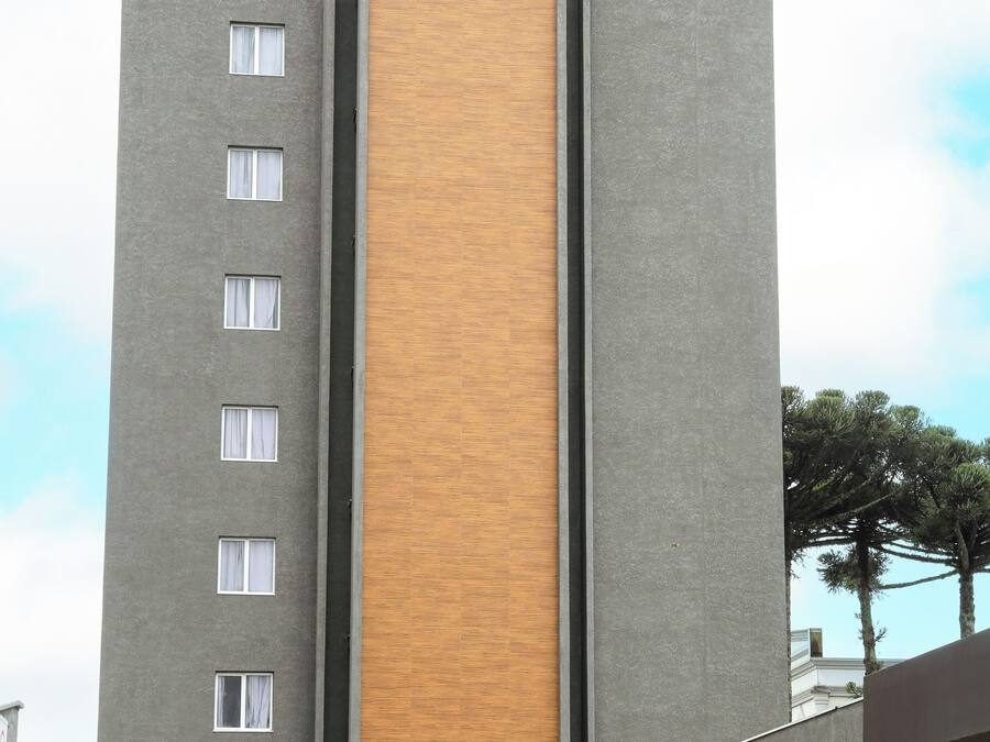 Un edificio moderno con un panel vertical de madera en el centro, múltiples ventanas y un letrero de 'SLAVIERO slim' en la entrada.