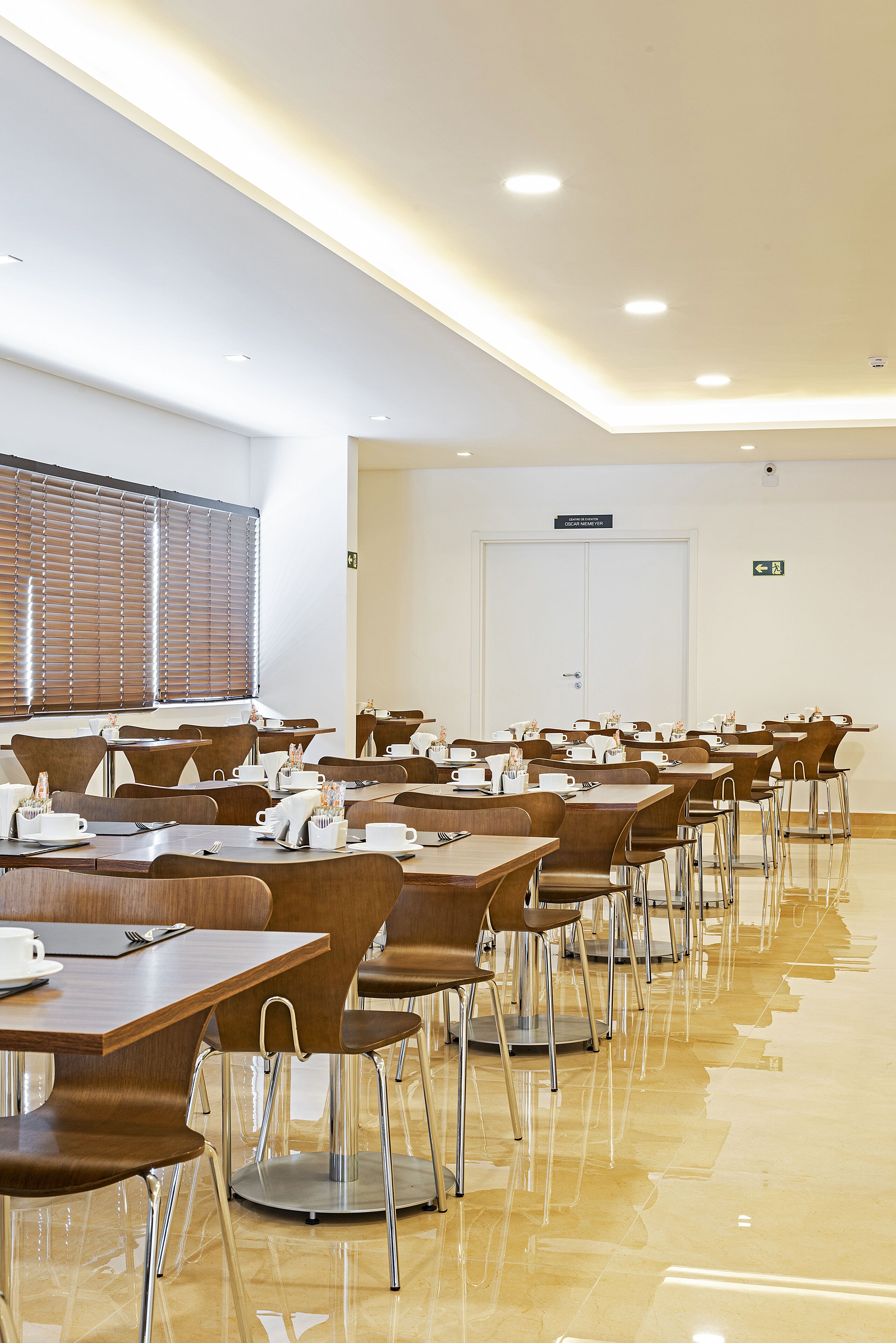 A conference room with multiple tables and chairs, equipped with nameplates and coffee cups.