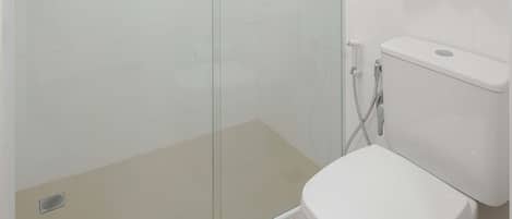 Un baño moderno con ducha de vidrio, inodoro blanco y una toalla colgada en la pared.