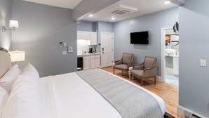 A bedroom with a bed, a desk, two chairs, a television, and a kitchenette. - The Outlook Inn (Newport)