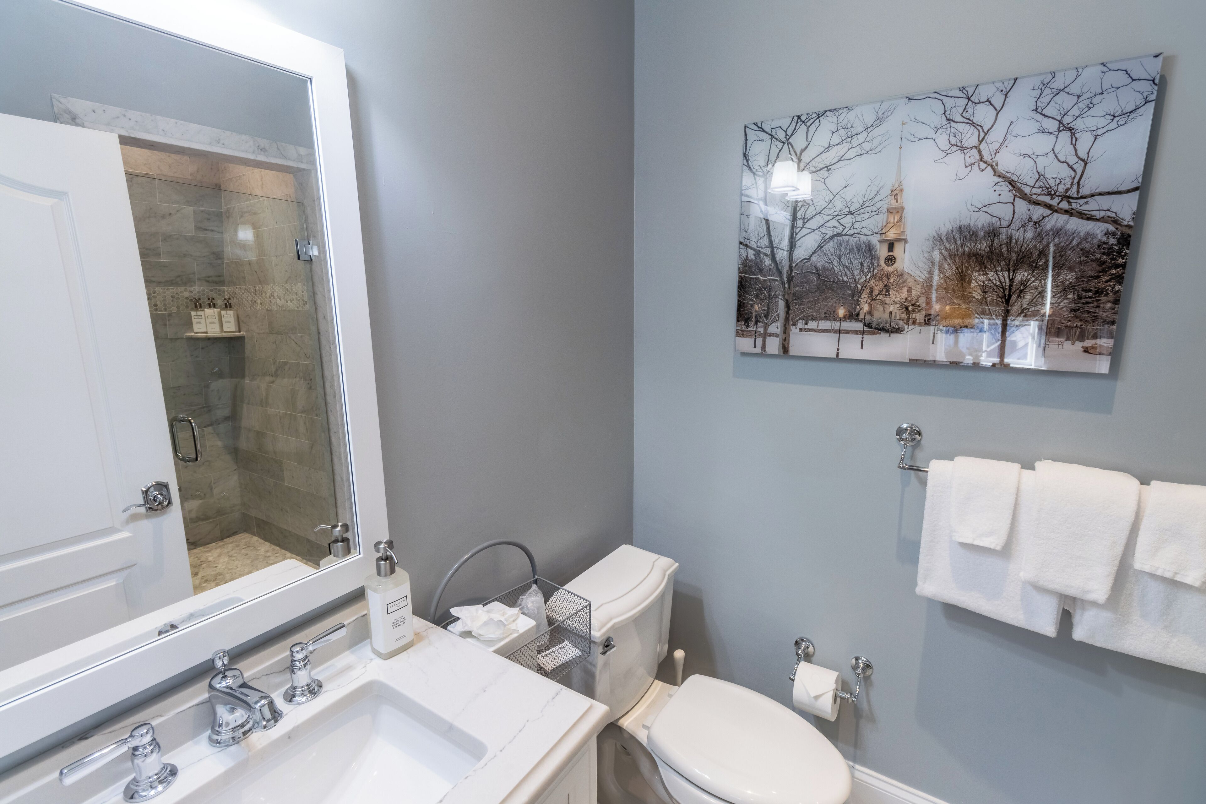 A bathroom with a marble sink, a glass-enclosed shower, a toilet, and a wall-mounted towel rack.