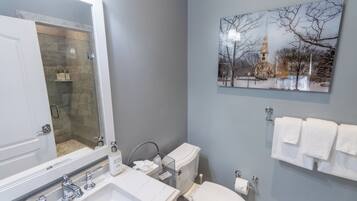 A bathroom with a marble sink, a glass-enclosed shower, a toilet, and a wall-mounted towel rack.