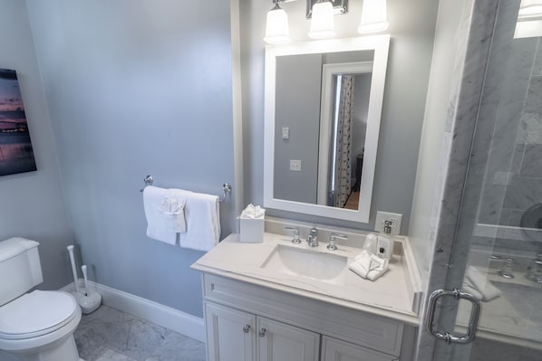 A bathroom with a white sink, a large mirror, and a shower area. - The Outlook Inn (Newport)