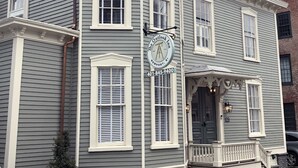 A corner building with a prominent sign for The Outlook Inn, featuring a classic architectural style with multiple windows and a stone foundation. - The Outlook Inn (Newport)