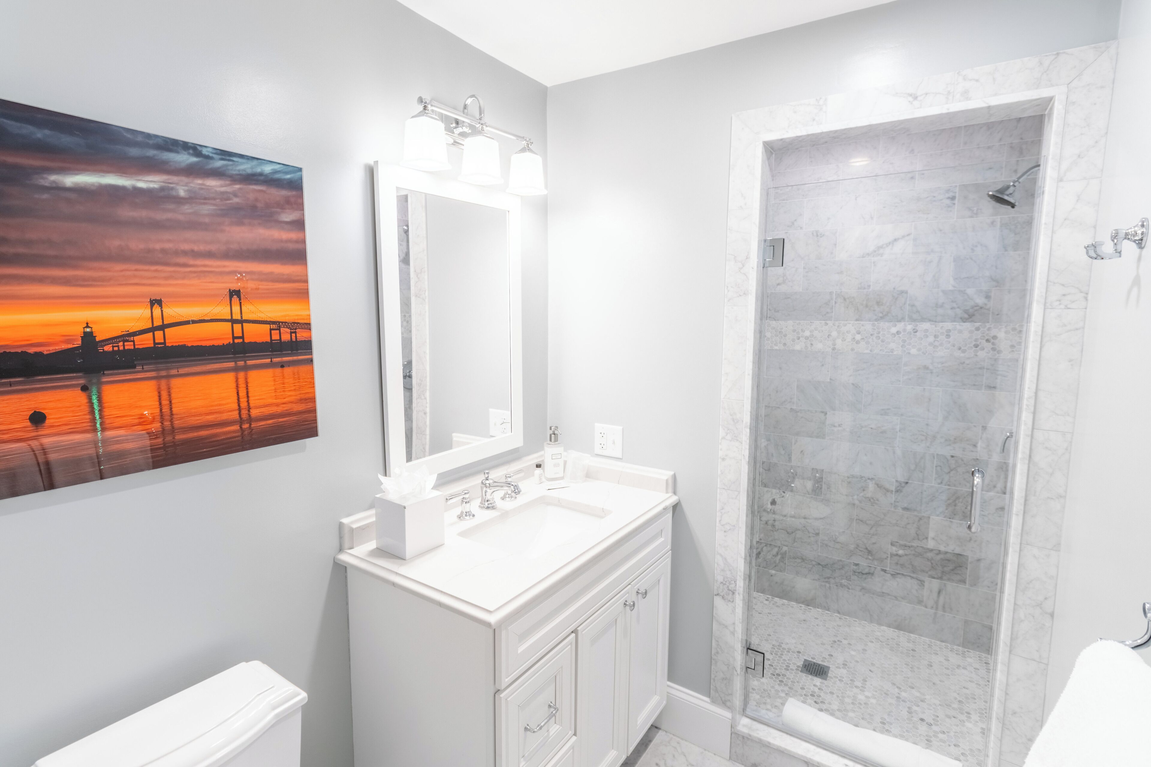 A modern bathroom with a large mirror, a sink, and a walk-in shower.