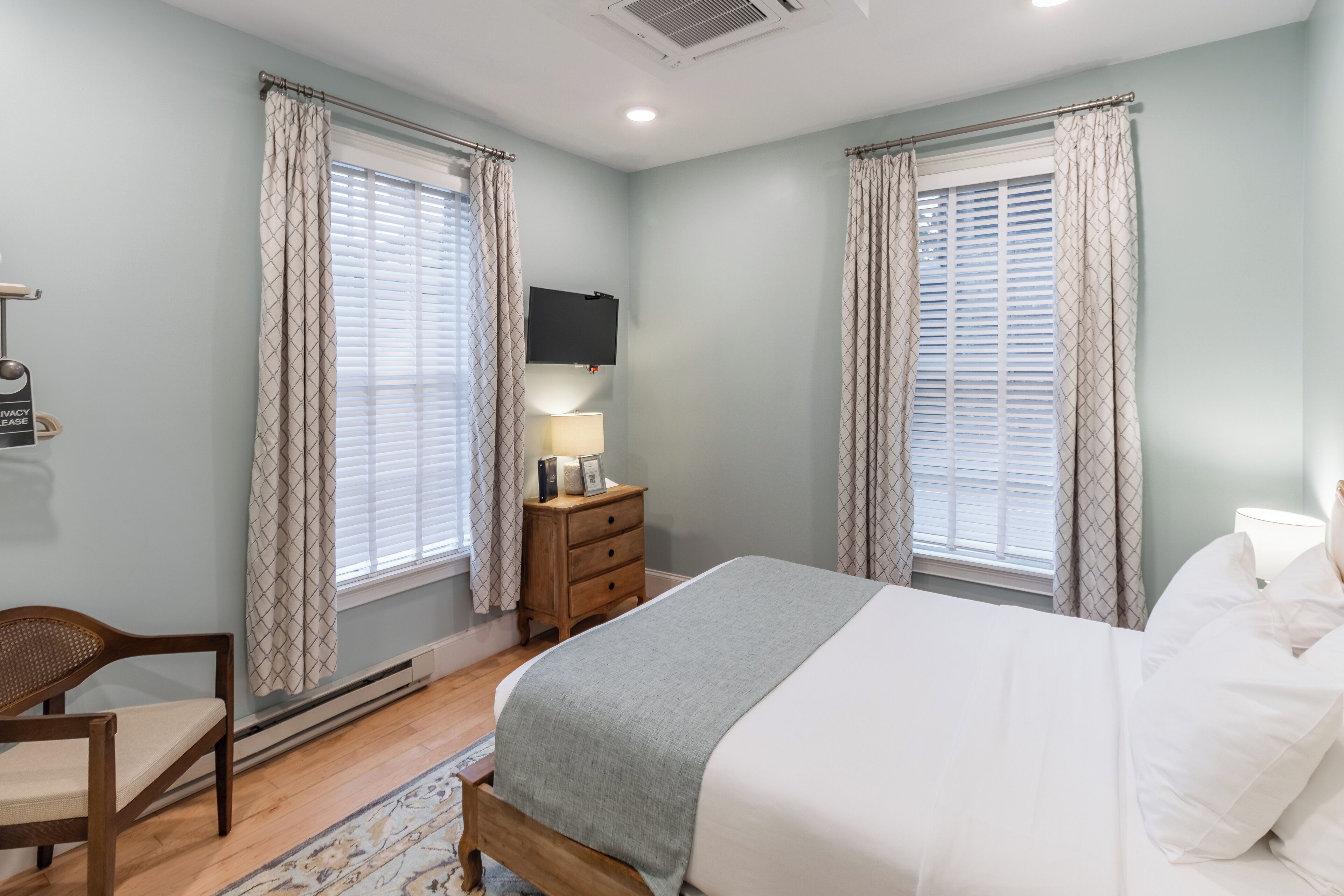A bedroom with a bed, a nightstand, a TV, and a chair.