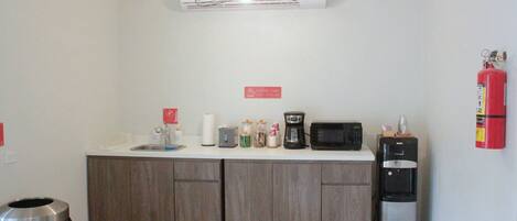 Une petite cuisine équipée d’un four à micro-ondes, d’une machine à café et d’un distributeur d’eau.