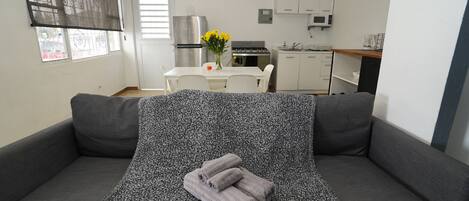 A modern living room with a grey sofa, a patterned throw, and a vase with yellow flowers.