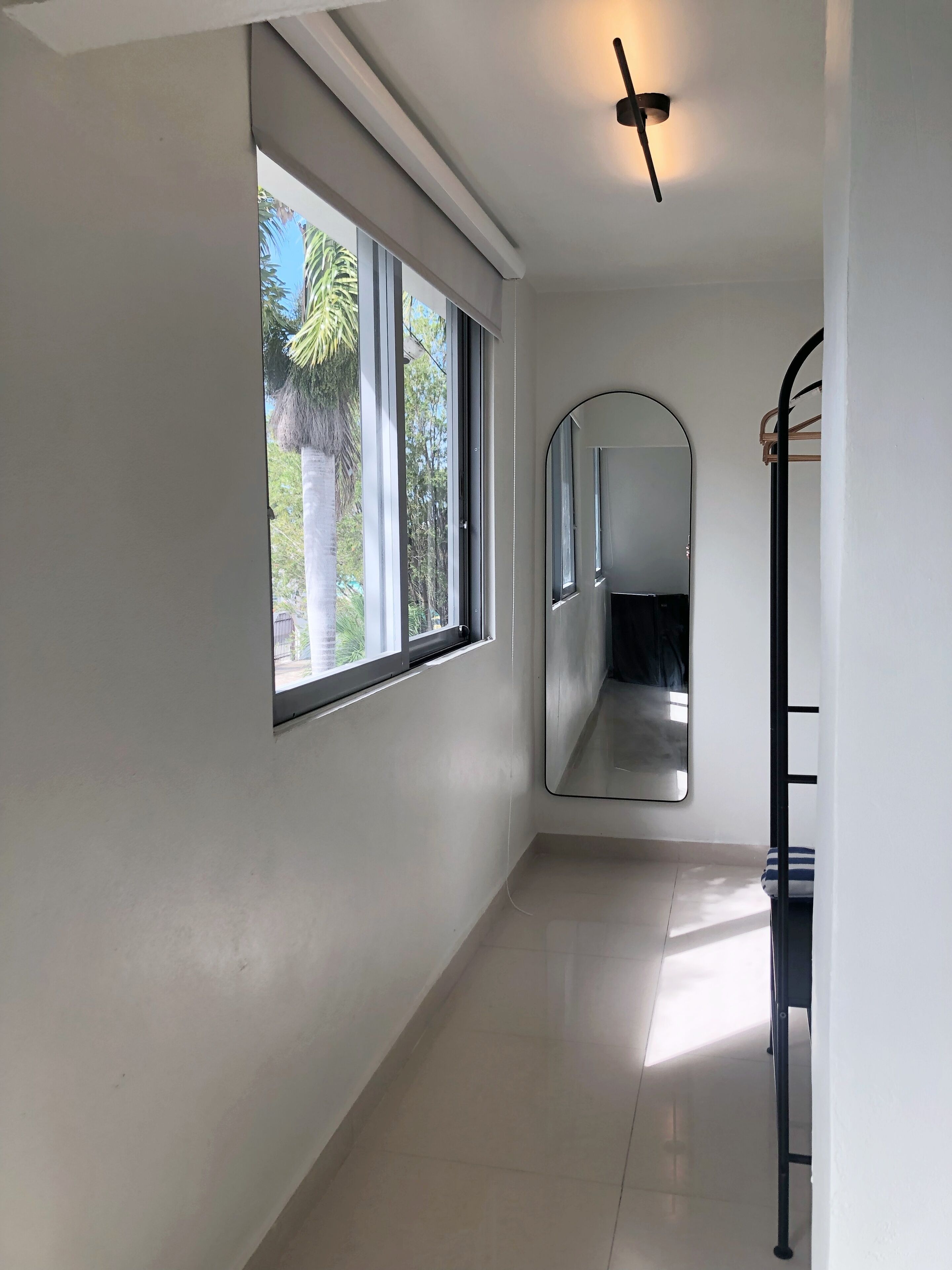 Un couloir avec une grande fenêtre, un ventilateur de plafond et un miroir.