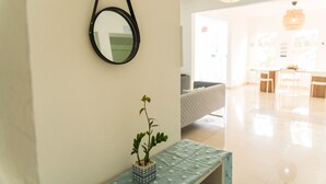 A modern living room with a hanging mirror, a small potted plant, and a bench. - Aura House Isla Verde (Carolina)