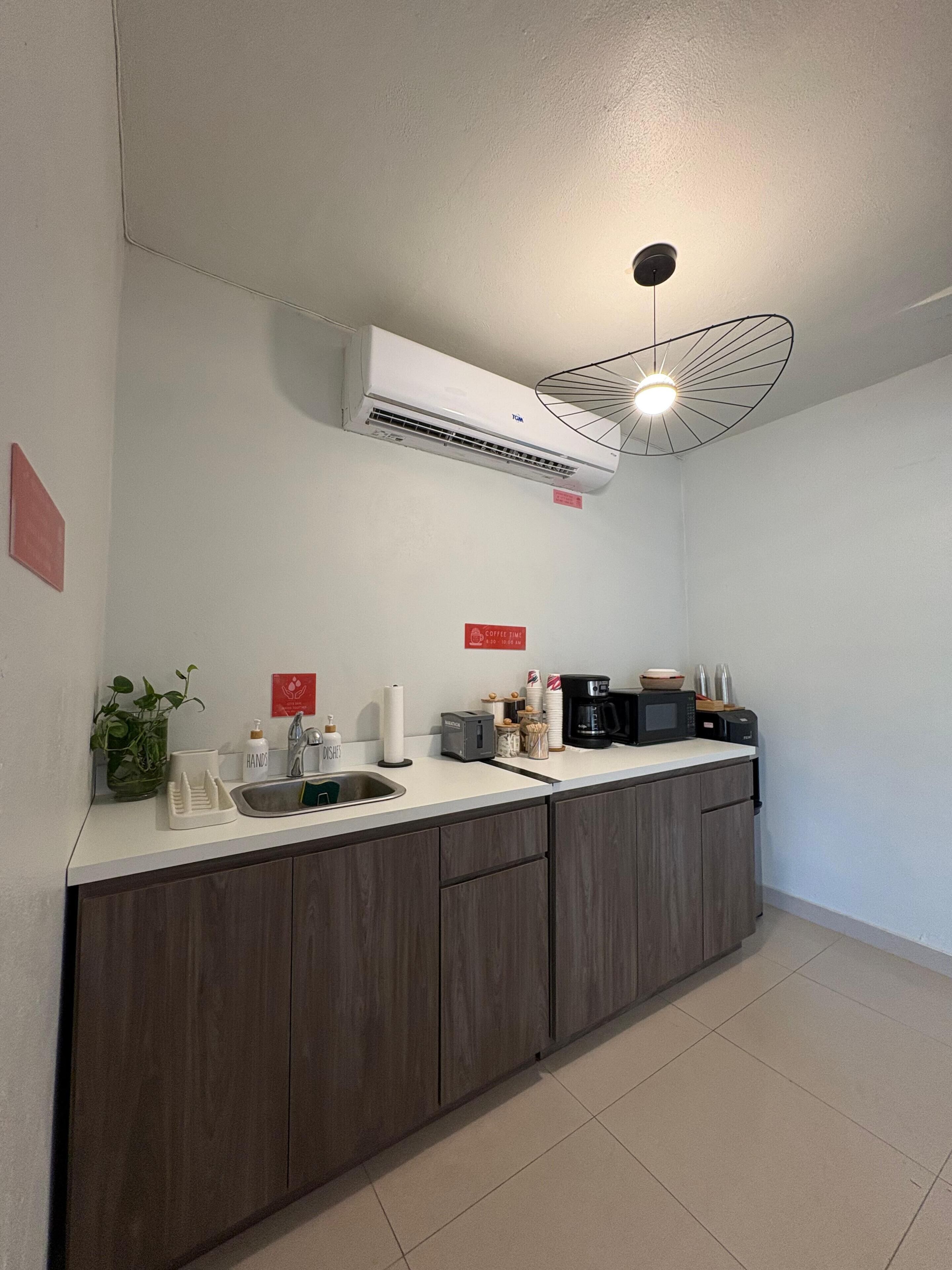 A modern kitchen with a built-in air conditioner, a sink, a coffee maker, and a microwave.