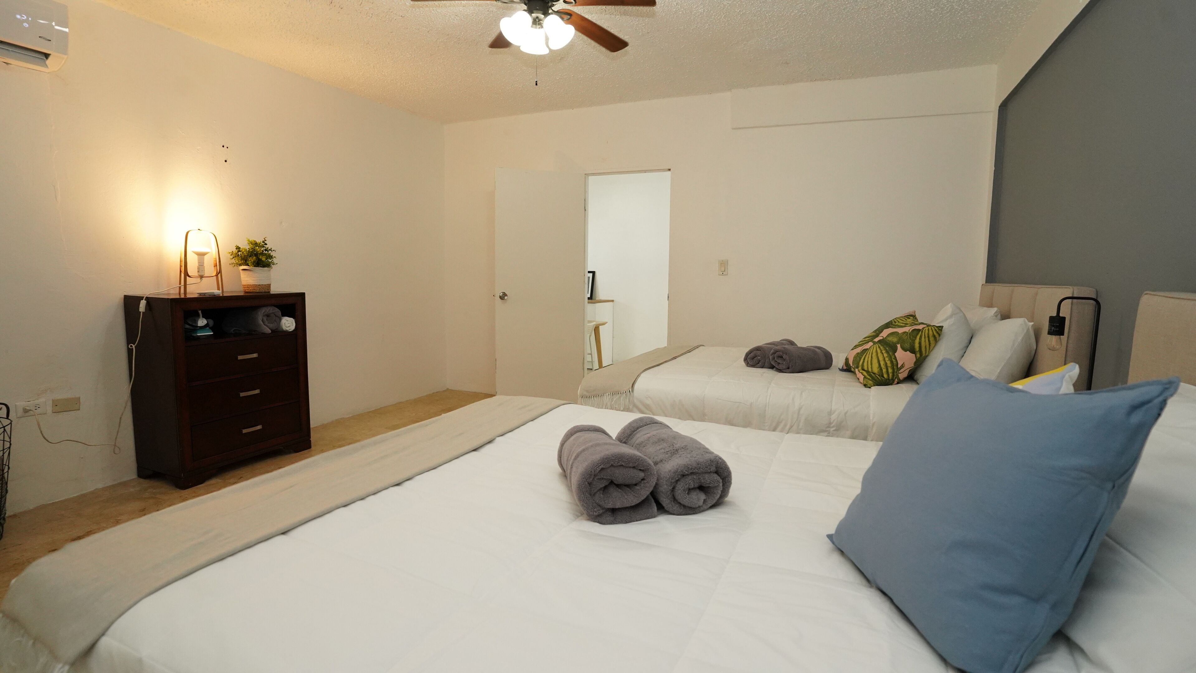 A bedroom with two beds, a dresser, a ceiling fan, and a mirror.