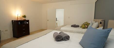 A bedroom with two beds, a dresser, a ceiling fan, and a mirror.
