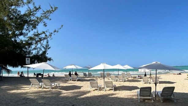 A beach with sun loungers and umbrellas, a clear sky, and the ocean in the background. - Aura House Isla Verde (Carolina)