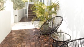 A patio with a herringbone brick floor, a black metal chair, and a glass table. - Aura House Isla Verde (Carolina)