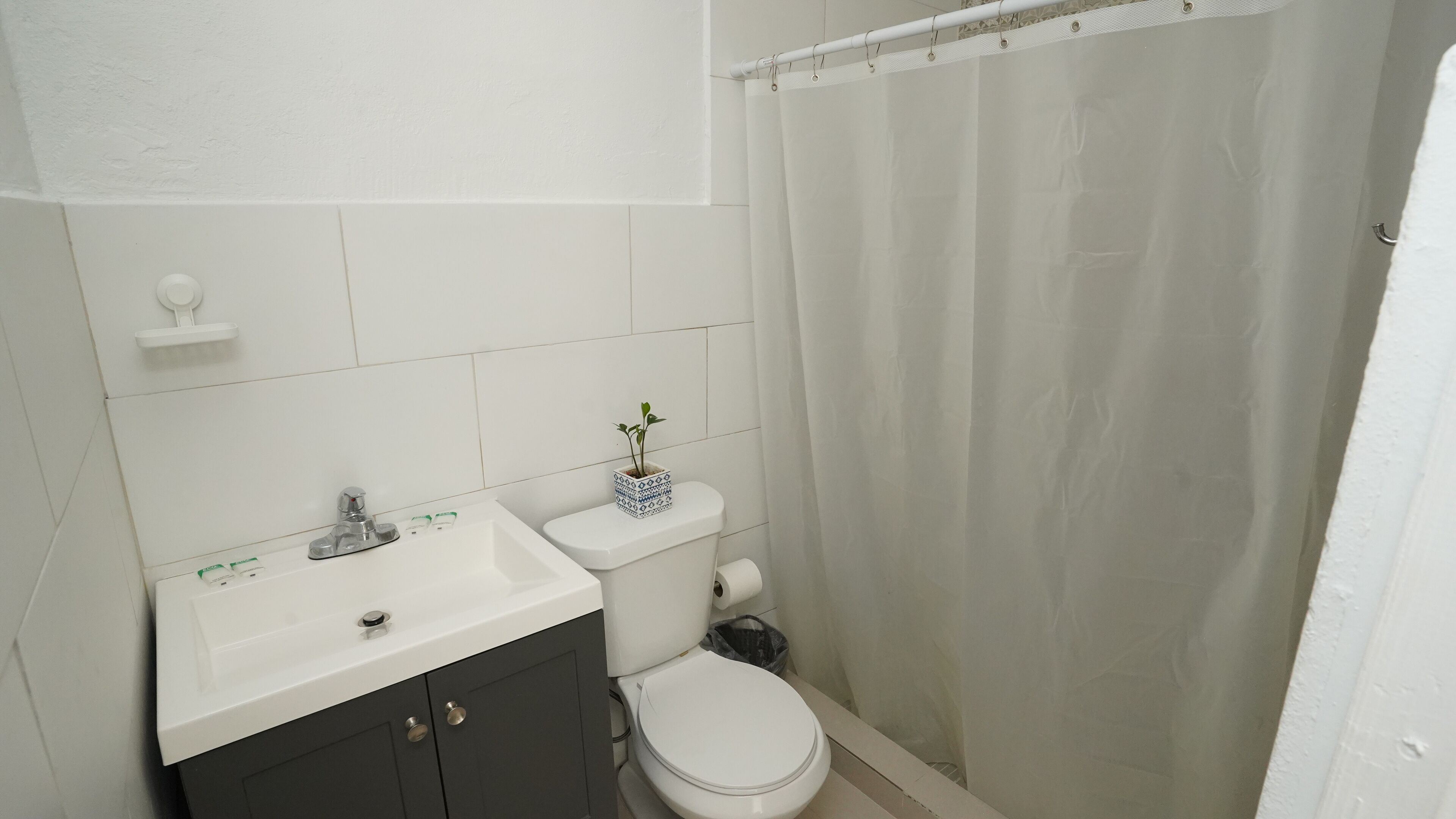 A bathroom with a white sink, dark cabinets, a toilet, and a shower curtain.
