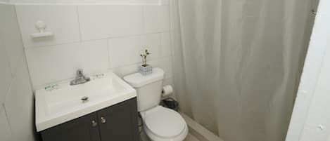 Et badeværelse med en hvid vask, mørke skabe, et toilet og en badeforhæng.