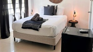 A neatly arranged bedroom with a bed, bedside table, and a hanging light fixture. - Aura House Isla Verde (Carolina)