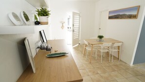A kitchen with a wooden table, white chairs, and a dining area with a view of the outside. - Aura House Isla Verde (Carolina)