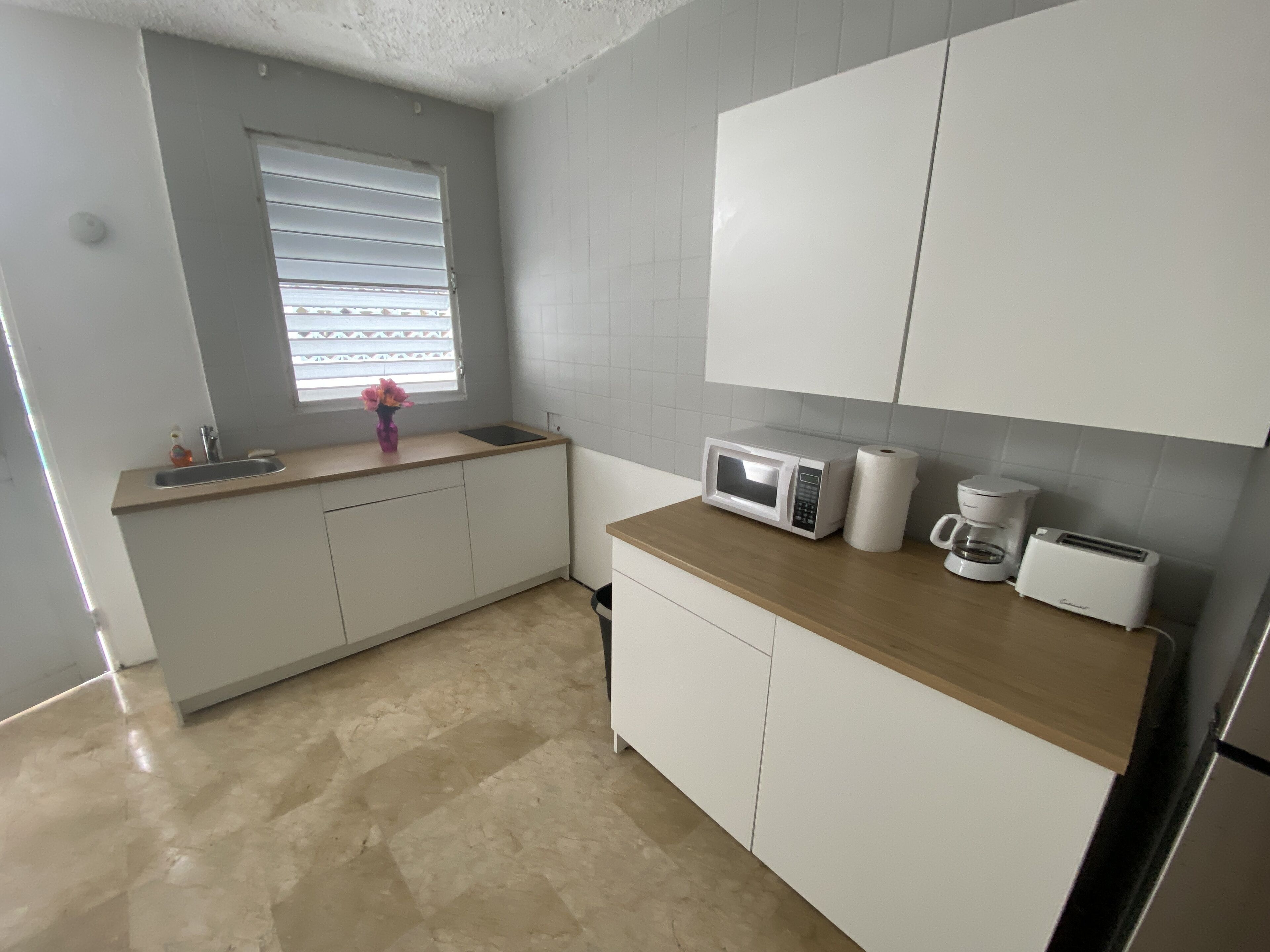 A modern kitchen with white cabinets, a microwave, a coffee maker, and a toaster.
