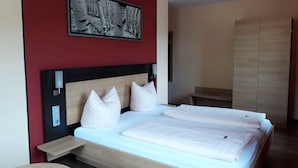 A modern bedroom with a wooden bed, white bedding, and a red accent wall. - Hotel & Restaurant La Baia (Cochem)