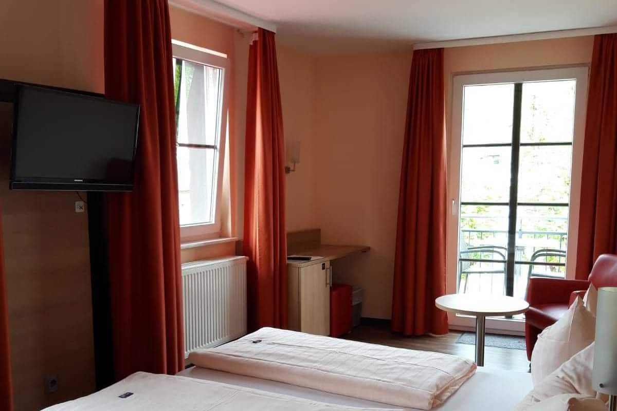 A hotel room with two beds, a TV, a small table, and a chair.