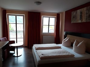 Una habitación de hotel con una cama, un escritorio y dos ventanas.
